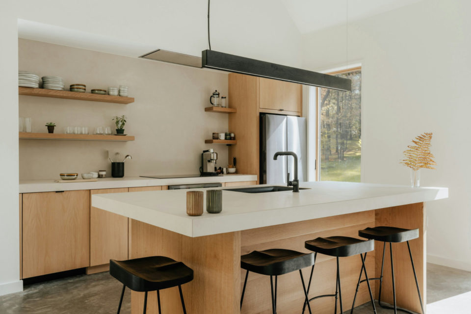 Photo d'une cuisine moderne en marbre et en bois avec un îlot central et une fenêtre donnant sur la nature - ArchiBienPensé, architecte d'intérieur à Annecy et en Haut-Savoie