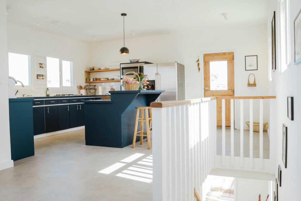 Intérieur lumineux d'une cuisine ouverte avec îlot central au sommet d'escaliers - ArchiBienPensé, architecte d'intérieur à Annecy et en Haut-Savoie