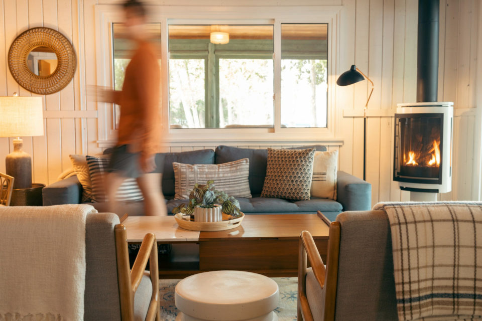 Photo de la silhouette d'une personne marchant dans son salon avec des canapés, une table en bois et une cheminée - ArchiBienPensé, architecte d'intérieur à Annecy et en Haut-Savoie